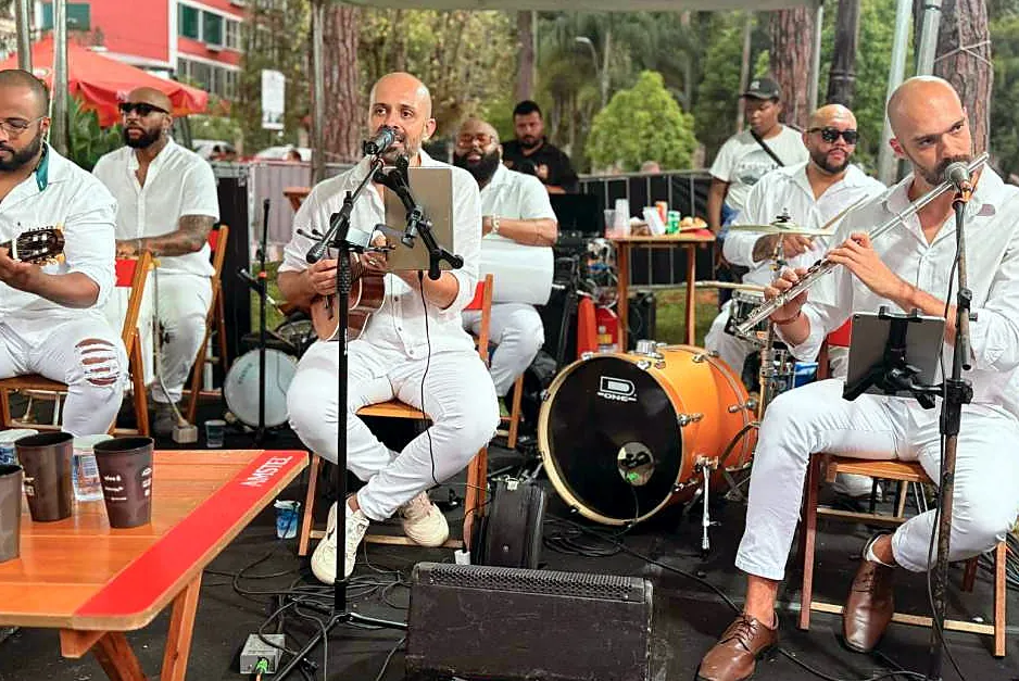 Grupo de samba vestido de branco tocando ao ar livre